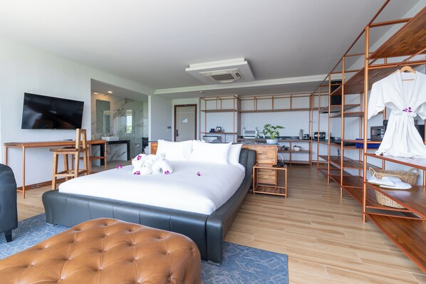 Una habitación de hotel moderna con una cama grande, un escritorio, un televisor y un pequeño espacio para cocinar.