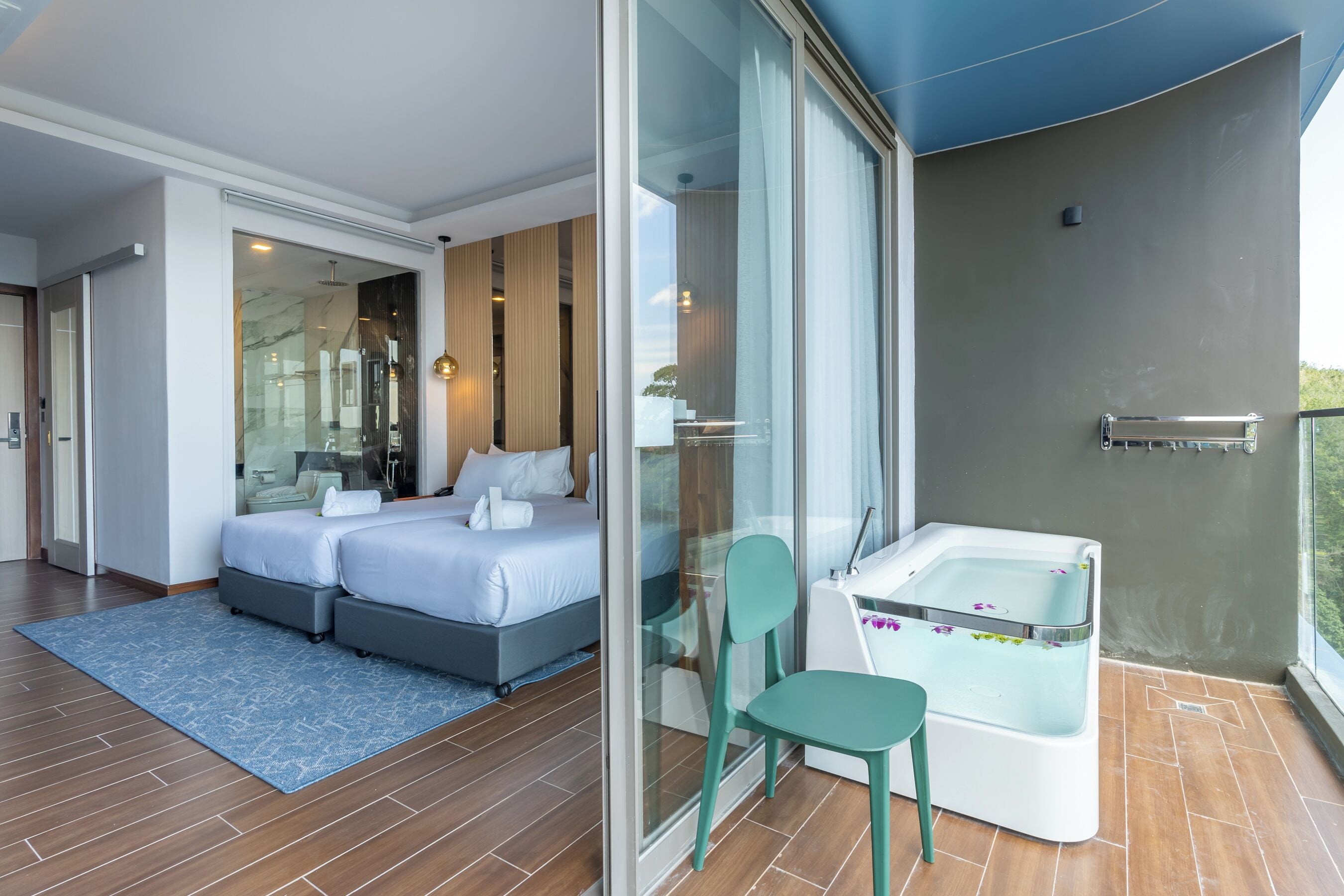 Un dormitorio moderno con una cama grande, un separador de vidrio, un jacuzzi y un balcón con vistas.