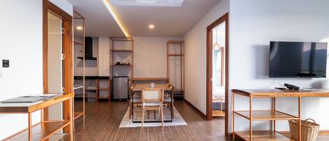 A modern kitchen with a dining area, wooden flooring, and a TV mounted on the wall.
