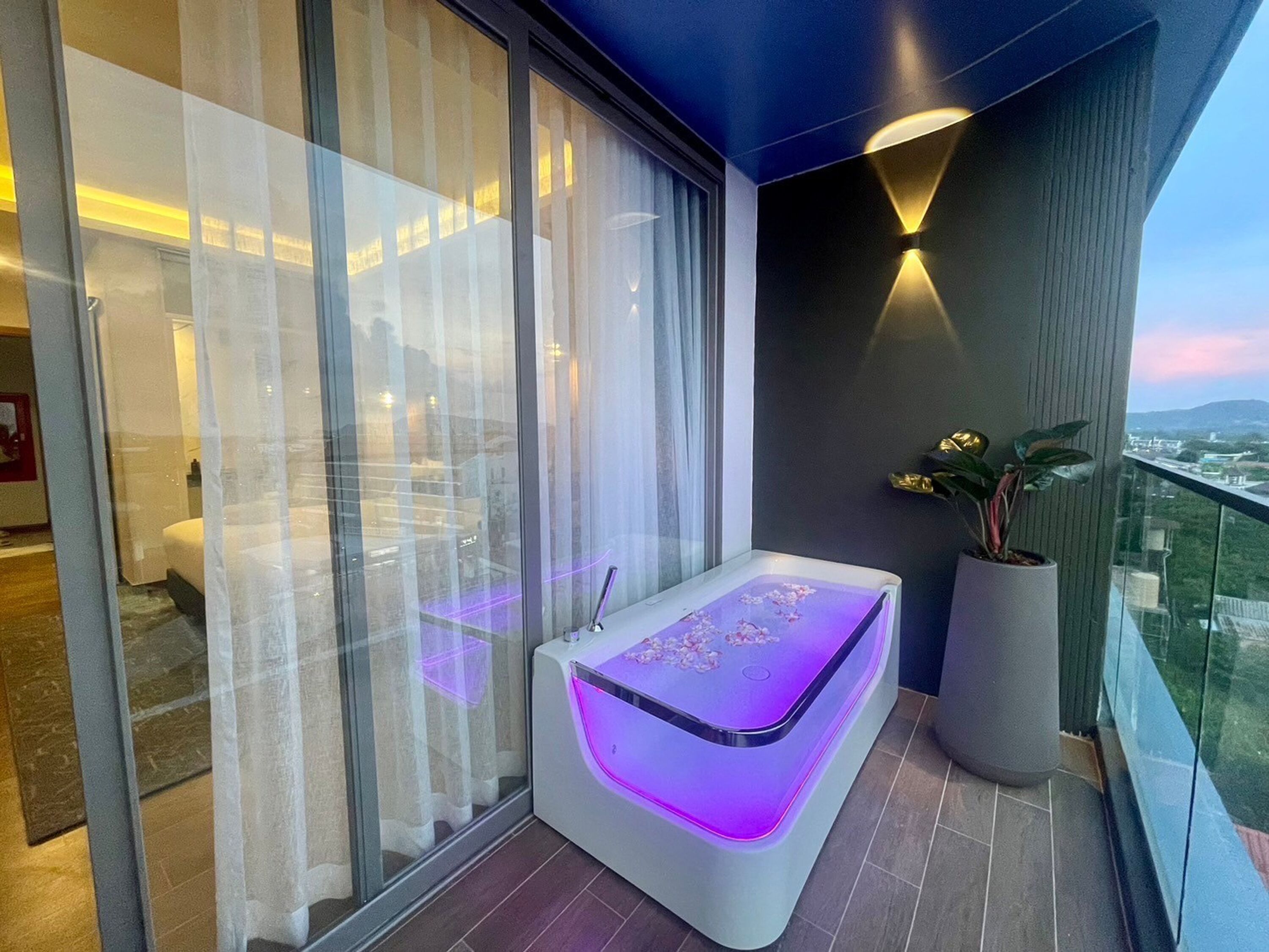 A modern balcony with a massage table, a potted plant, and a city view.