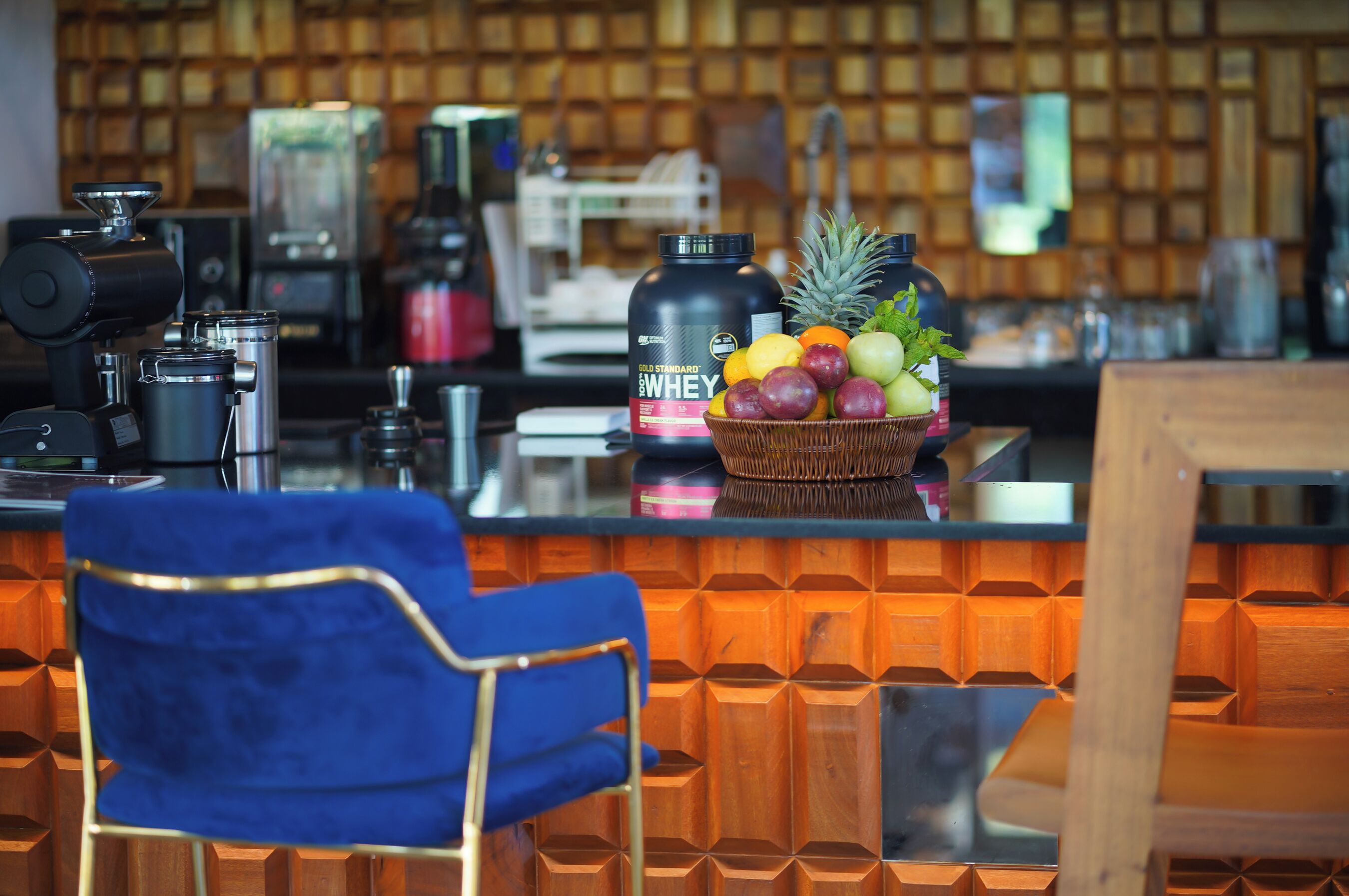 A bar area with a coffee machine, a blender, and a fruit basket on the counter.