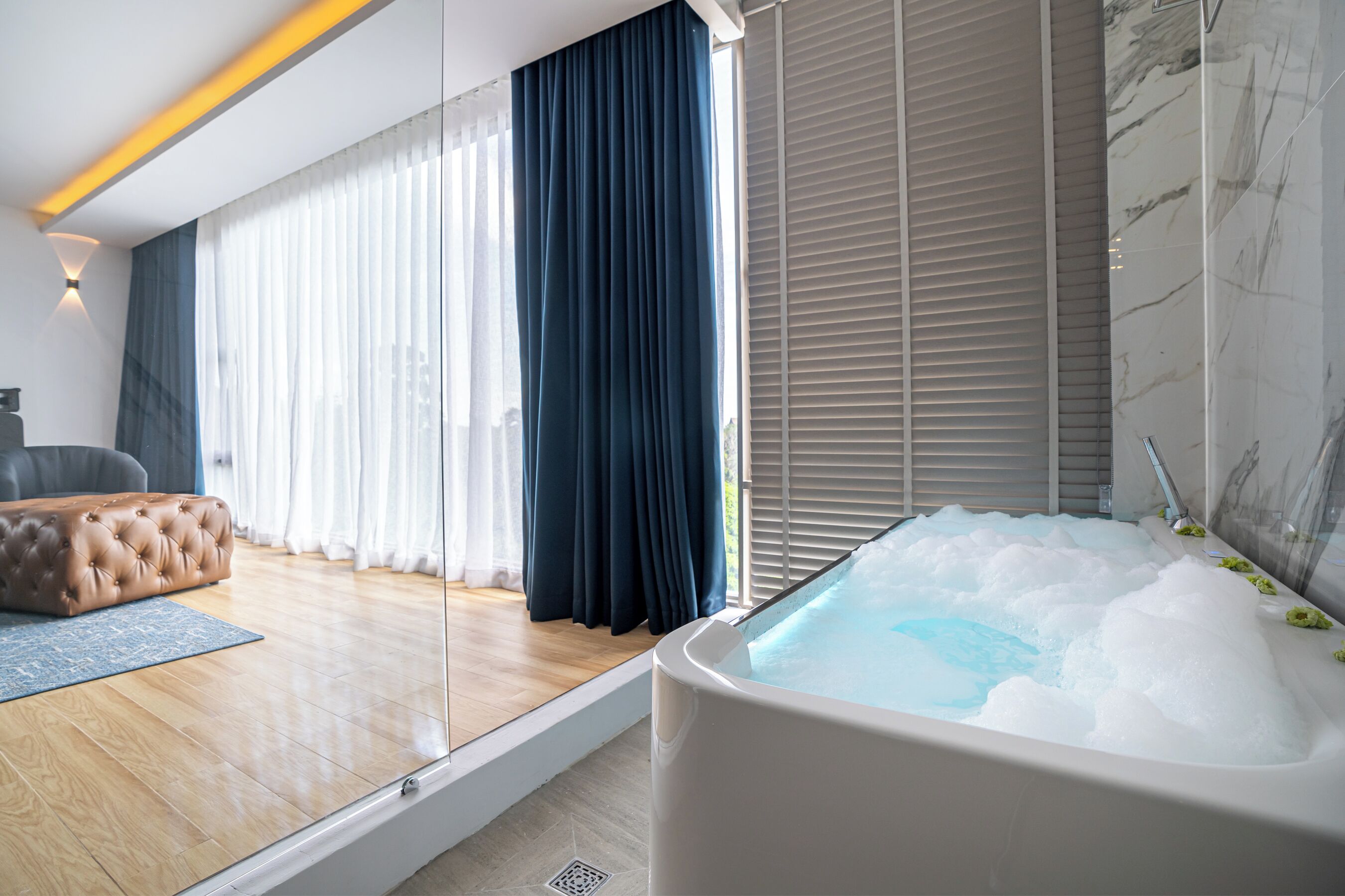 Un bagno moderno con una vasca da bagno ampia, pavimento in legno e vista all'esterno grazie a grandi finestre.