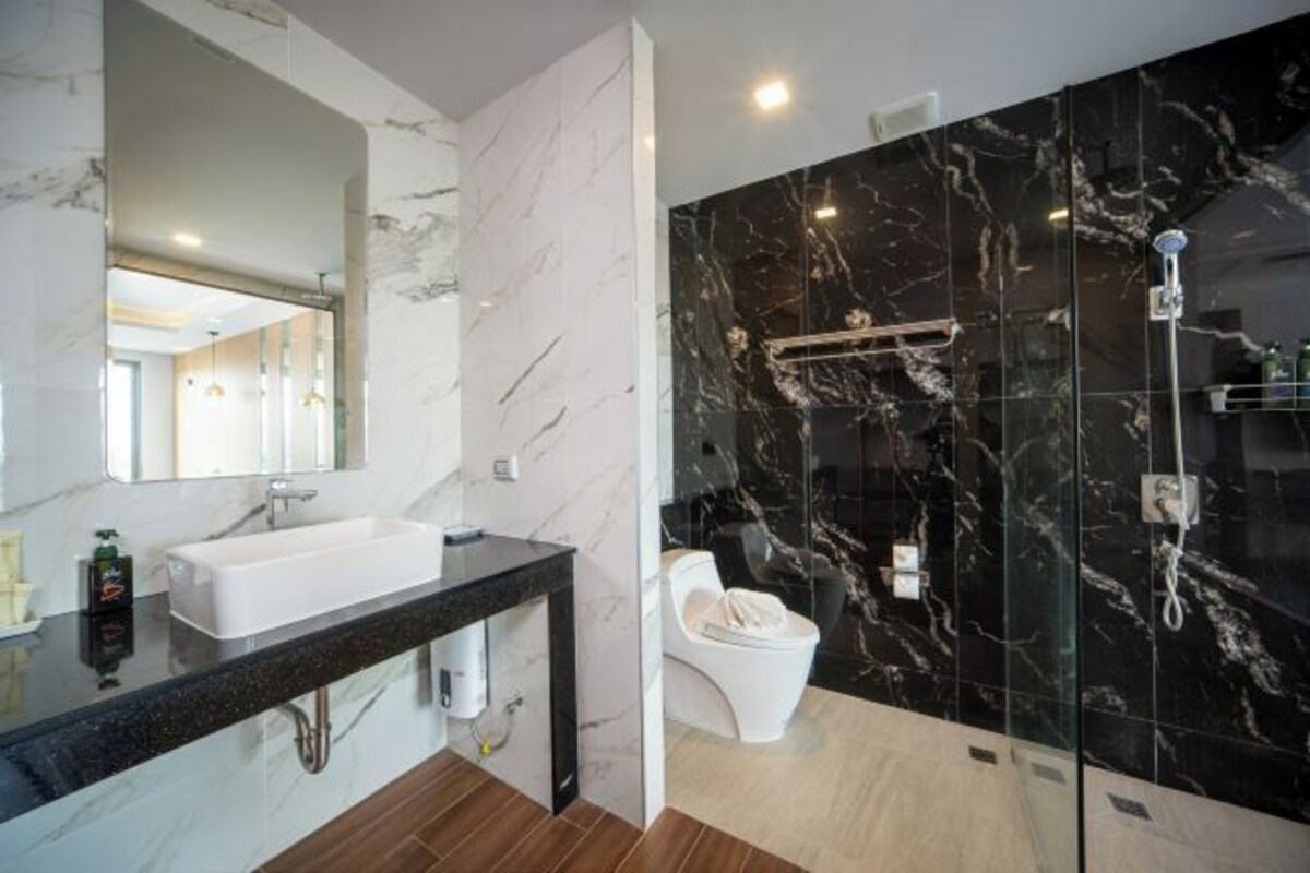 A modern bathroom with a marble vanity, a glass shower enclosure, and a toilet.
