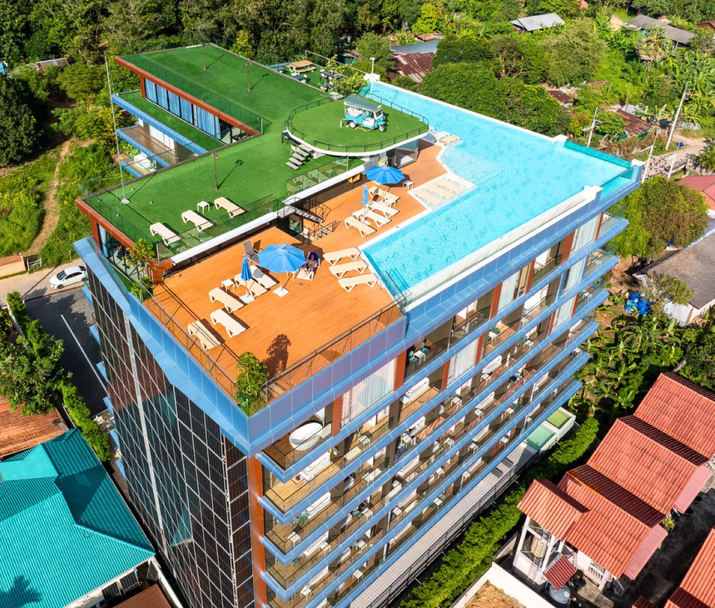 Un hôtel à plusieurs étages doté d’une piscine sur le toit, d’un espace extérieur aménagé et d’un jardin luxuriant.