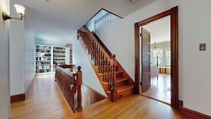 A wooden staircase with a railing, leading to a room with a bed and a window. - Seven Gables by Bayley Vacation Rentals (Kennebunk)
