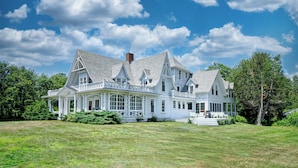 A large, white, two-story house with a wrap-around porch and multiple windows. - Seven Gables by Bayley Vacation Rentals (Kennebunk)