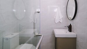 A modern bathroom with a glass shower enclosure, a white sink, and a large mirror. - Raya Hotel Krabi (Krabi)