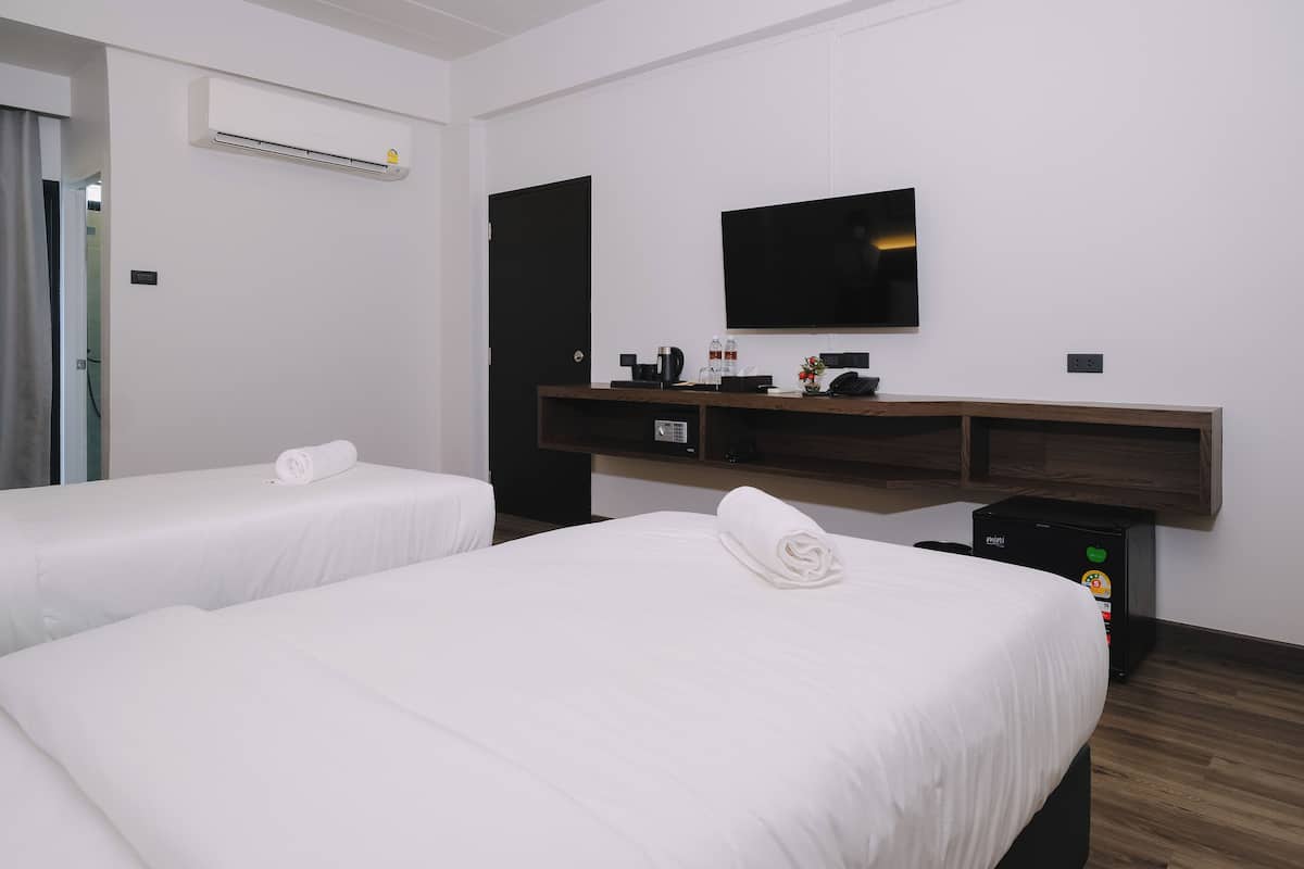 Une chambre d’hôtel avec deux lits, un téléviseur à écran plat, un bureau avec une imprimante et un appareil de climatisation.