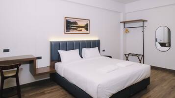 A modern hotel room with a bed, a desk, and a chair.