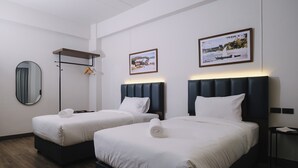 A hotel room with two beds, a mirror, a small table, and two framed pictures on the wall. - Raya Hotel Krabi (Krabi)