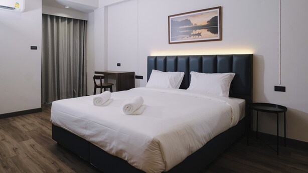 A hotel room with a large bed, a desk, a chair, and a painting on the wall. - Raya Hotel Krabi (Krabi)