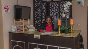 A reception desk with a no smoking sign, a television, and a decorative plant. - The Grill House & Suites Asokoro Abuja (Abuja)