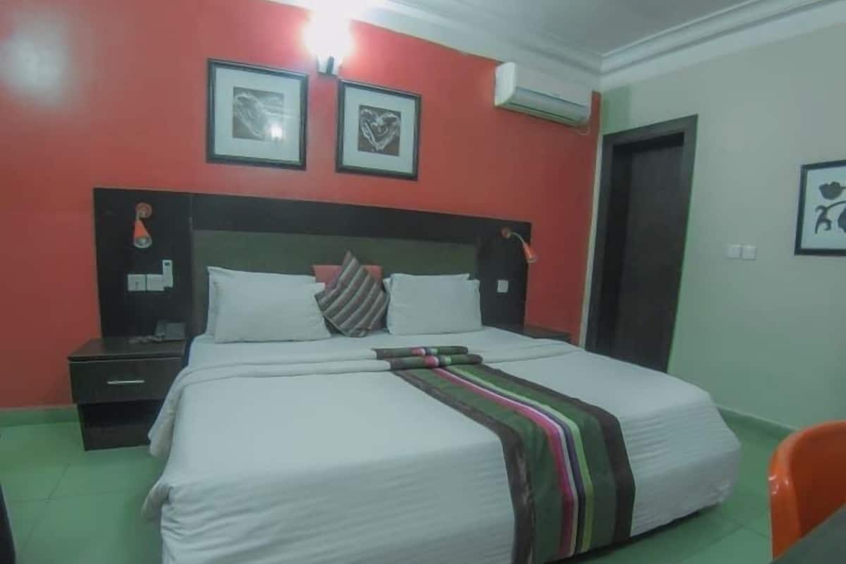 A hotel room with a bed, a nightstand, a chair, and a door.
