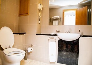 A modern bathroom with a toilet, sink, and towel rack. - The Grill House & Suites Asokoro Abuja (Abuja)