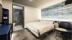 Een moderne hotelkamer met een bed, een bureau, een stoel en een groot abstract schilderij aan de muur.