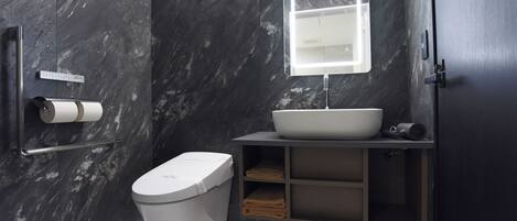 Ein modernes Badezimmer mit Marmorwand, Toilette, Waschbecken mit Spiegel und Handtuchhalter.