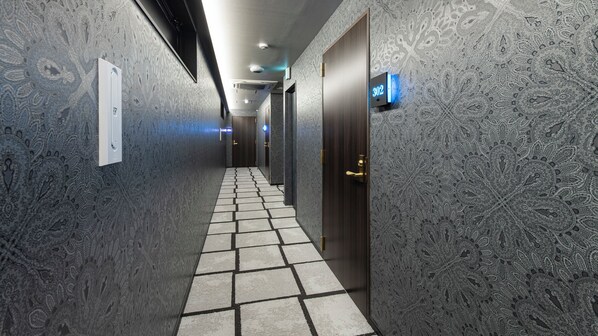 A hallway with patterned walls, a tiled floor, and a door with a digital sign. - Gion Shijo Hotel  (Kyoto)