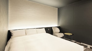 A modern hotel room with a large bed, a chair, and a small round table.