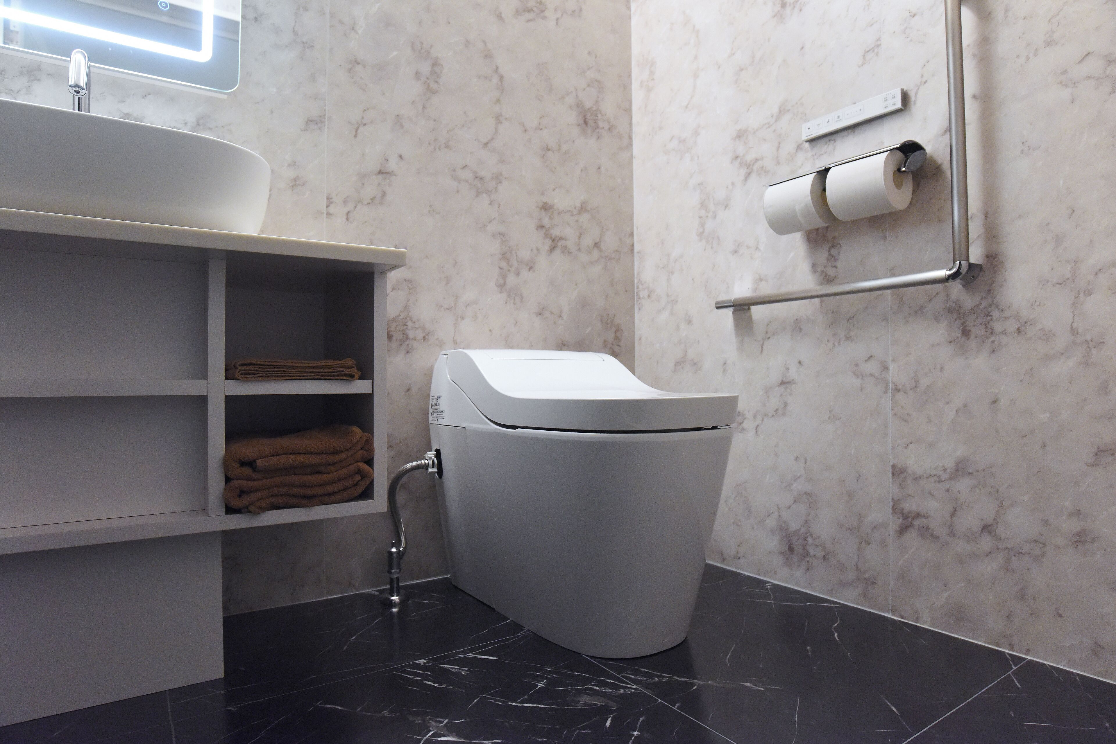 A modern bathroom with a toilet, a sink, and a towel rack.
