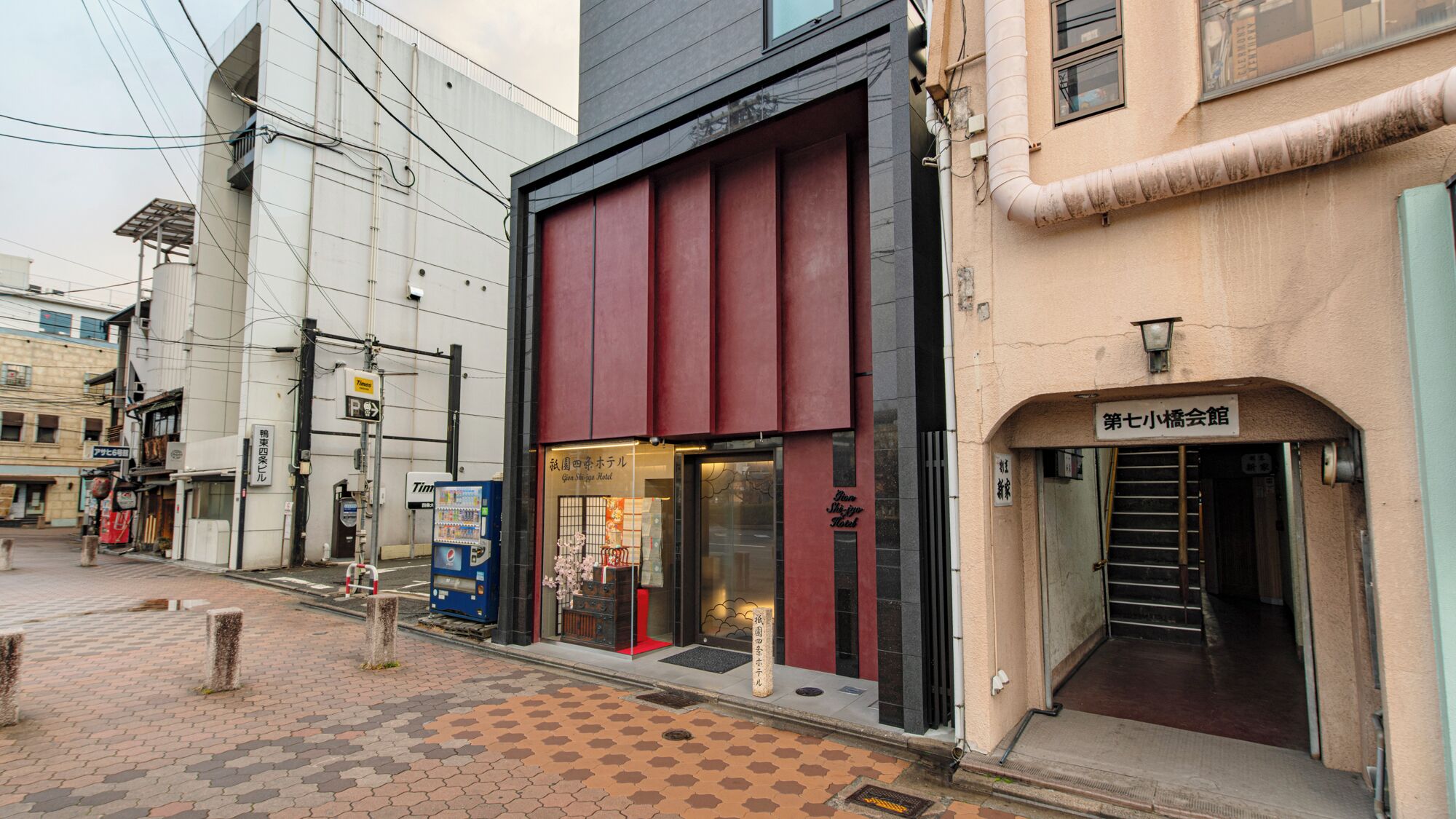 A hotel with a modern facade, a visible entrance, and a sign indicating it is the seventh hotel in the chain.