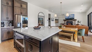 A modern kitchen with dark wooden cabinets, a stainless steel refrigerator, and a marble countertop. - 4BR w hot tub, gas fireplace, near NAU (Flagstaff)