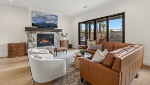 A modern living room with a fireplace, comfortable seating, and large windows. - 4BR w hot tub, gas fireplace, near NAU (Flagstaff)