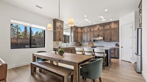 A modern kitchen with wooden cabinets, a dining area with a bench, and a large window. - 4BR w hot tub, gas fireplace, near NAU (Flagstaff)