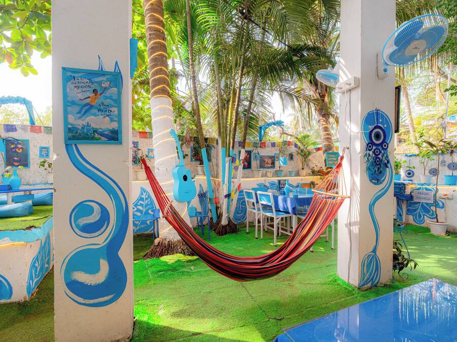 Una hamaca en un espacio de temática tropical con murales coloridos y palmeras.