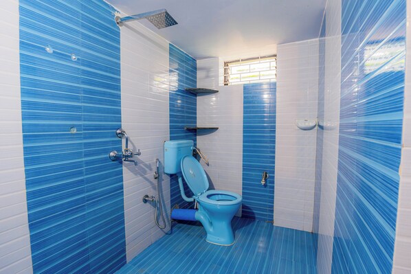 A bathroom with blue-striped tiles, a toilet, a shower, and a small window. - Viik wellness inn 3-Star Resort in Arambol Beach (Arambol)