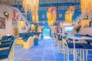 A modern lounge area with blue and white furnishings, hanging decorations, and a television screen. - Viik wellness inn 3-Star Resort in Arambol Beach (Arambol)
