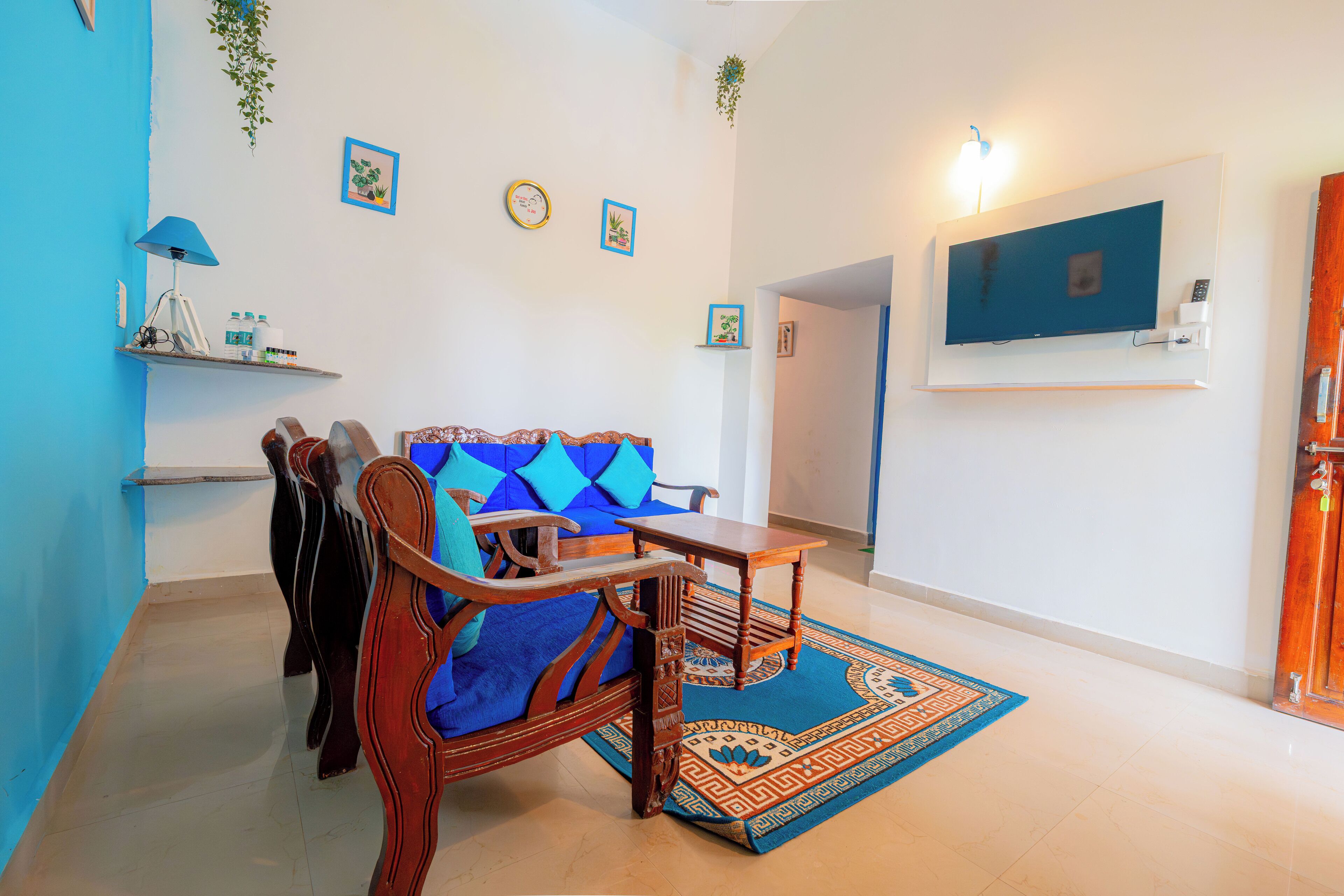 A living room with a blue sofa, wooden coffee table, and a TV mounted on the wall.