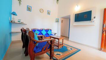A living room with a blue sofa, wooden coffee table, and a TV mounted on the wall.