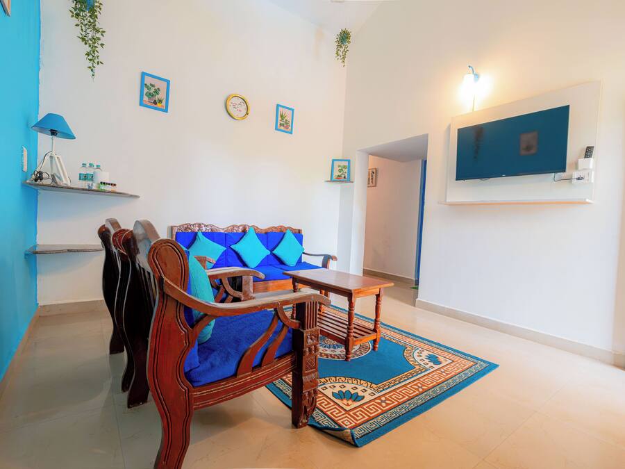 A living room with a blue sofa, wooden coffee table, and a TV mounted on the wall.