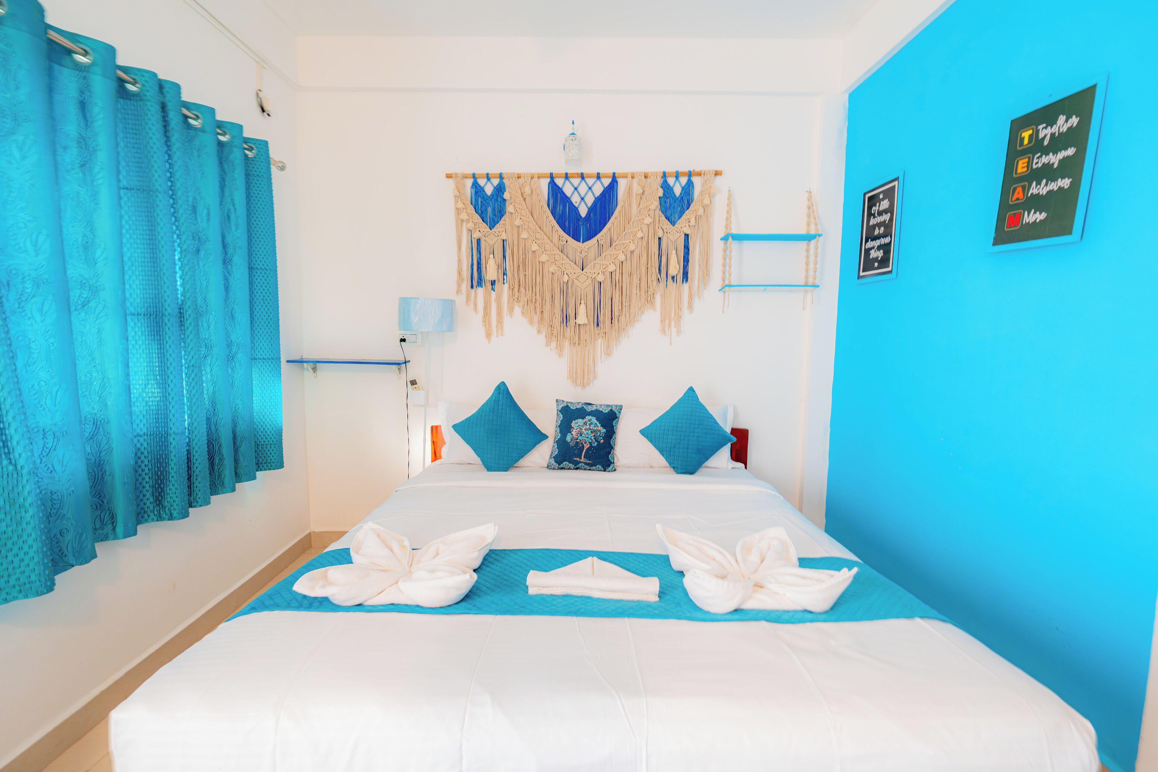 A hotel room with a bed, a blue wall, and a decorative headboard.
