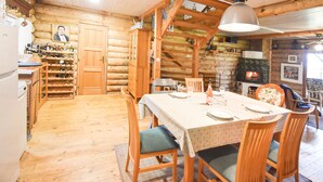 A log cabin interior with a dining area, wooden walls, a fireplace, and a wine rack.