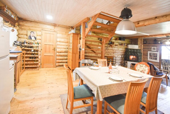 A log cabin interior with a dining area, wooden walls, a fireplace, and a wine rack.