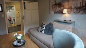 A living room with a sofa, a lamp, and a painting on the wall.