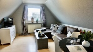 Ein modernes Loft-Apartment mit Schlafgalerie, einer Couch, einem Esstisch und einem Fernseher auf einer Kommode.