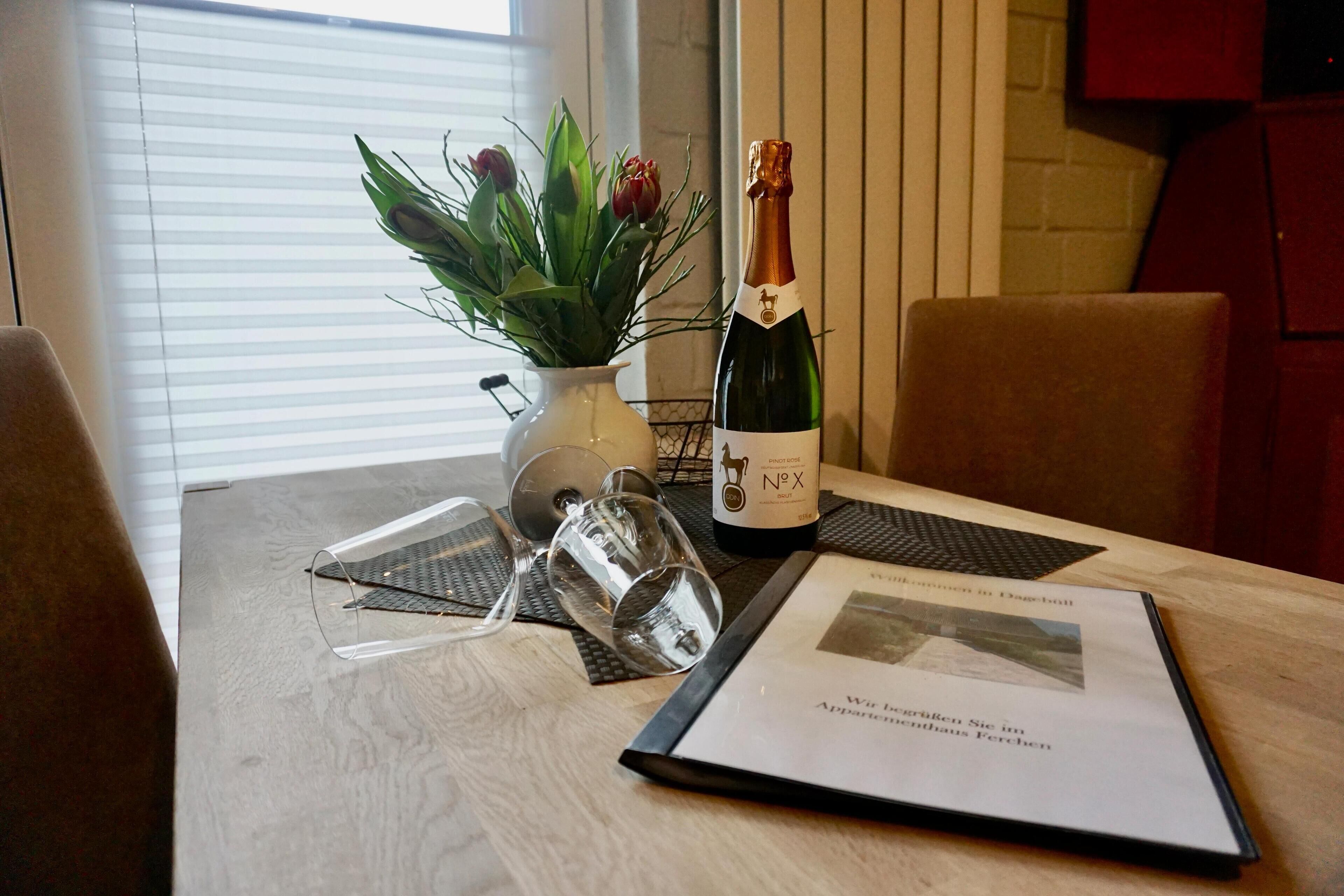 Ein Tisch mit einer Champagnerflasche, einer Blumenvase und einer Speisekarte.