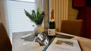 Une table avec une bouteille de champagne, un vase de fleurs et un menu.