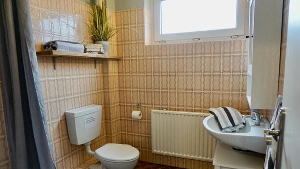 Un baño con inodoro, lavamanos, radiador y ventana.