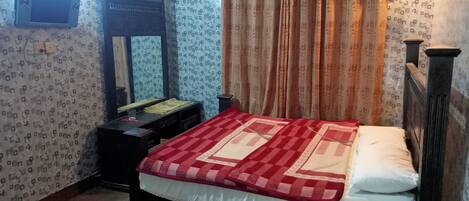 A bedroom with a bed, a dresser, a mirror, and a window with curtains.