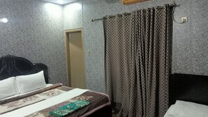 Ein Hotelzimmer mit einem Bett, einem Deckenventilator, strukturiertem Wandpapier und einer Klimaanlage.