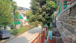 Eine enge Straße mit einem stehenden Auto, einer Treppe mit einer gemusterten Wand und einem Baum im Vordergrund.