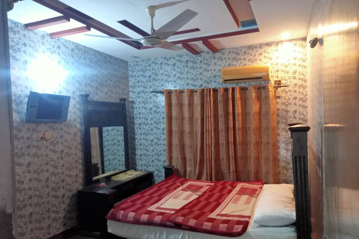 Une chambre à coucher avec un lit, un ventilateur de plafond, un miroir et un papier peint à motifs.