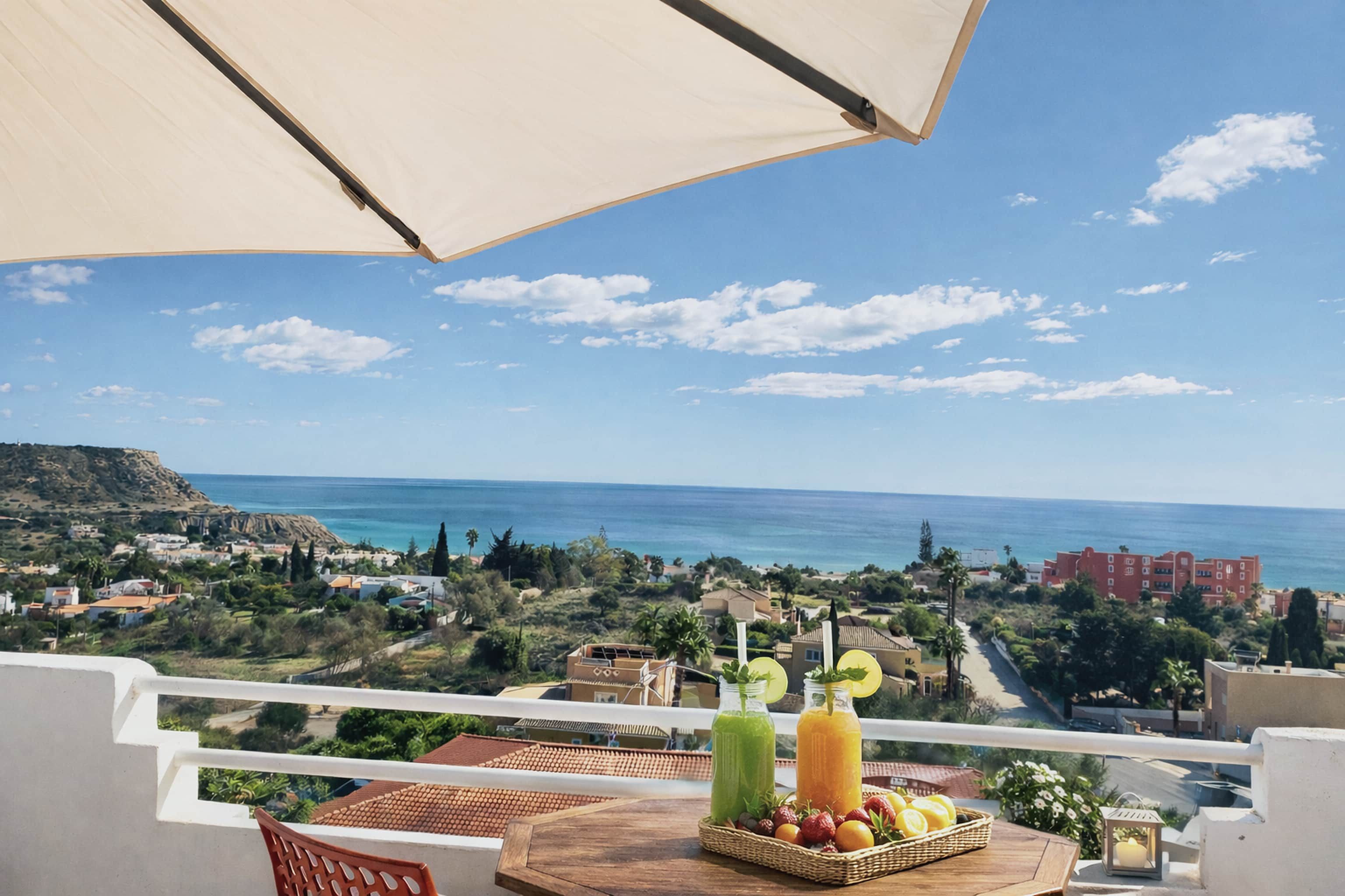 A balcony with a table, two bottles of drinks, and a basket of fruit.
