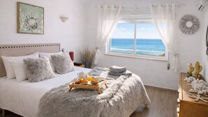 A bedroom with a bed, breakfast tray, and a view of the sea. - Bela Vista Apartment (Luz)