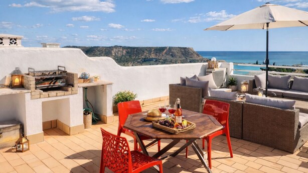 An outdoor patio with a grill, seating, and a view of the sea. - Bela Vista Apartment (Luz)