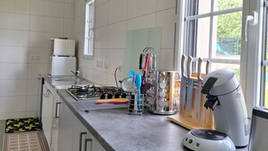 Eine moderne Küche mit weißen Schränken, einer Edelstahl-Arbeitsplatte und einem Fenster, das für natürliches Licht sorgt.