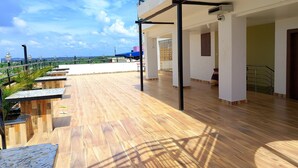 Une vaste terrasse sur le toit, dotée d’un plancher en bois et offrant une vue sur le paysage urbain.